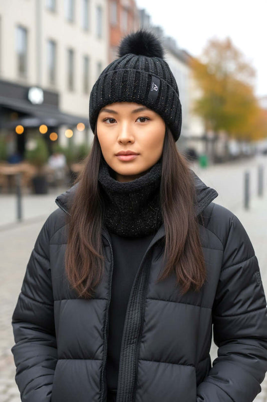 Women wearing a stylish black winter Kiki beanie and neck warmer on a city street, showcasing cozy winter fashion.