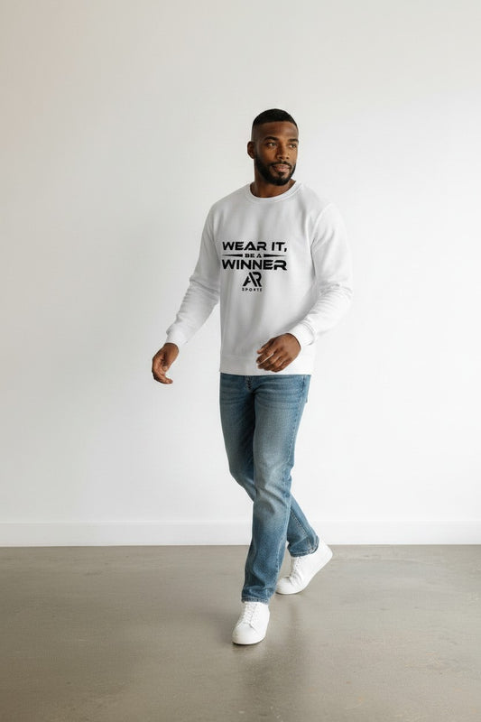 A man wearing a round neck sweater with the text 'WEAR IT, WINNER' walking in jeans and sneakers.