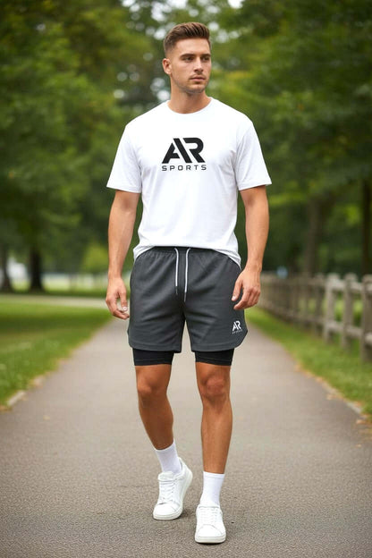 Model wearing men's compression above knee gym shorts with a white t-shirt and sneakers on a pathway.