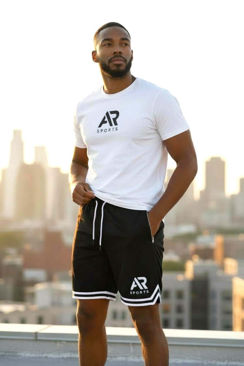 Men's long basketball and gym shorts worn by a man against a city skyline background.