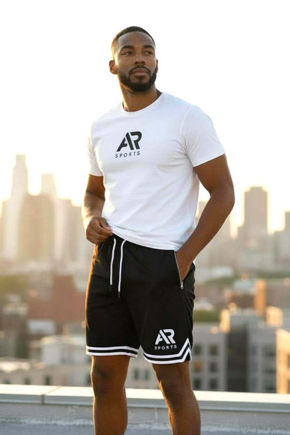 Men's long basketball and gym shorts worn by a man against a city skyline background.